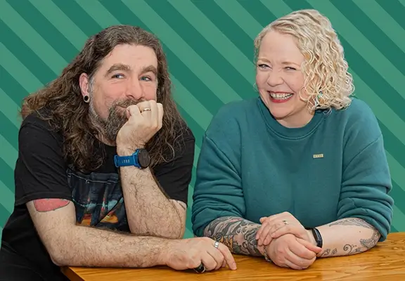 Rob Bee and Helen Bee sat leaning on a table, both giggling looking at the camera.